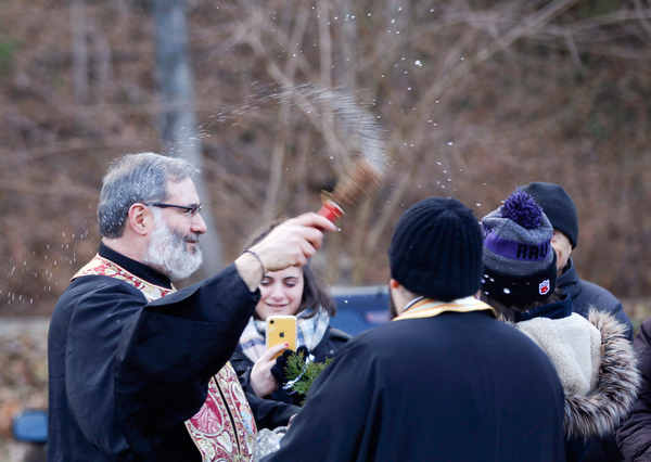 Father Tom Constantine blesses attendees with holy water during the Blessing of the Waters Service at Lake Glacier in Mill Creek Park on Sunday afternoon. EMILY MATTHEWS | THE VINDICATOR