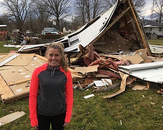 > Emily Metheny stands near the garage that was over a pickup truck on  her grandfather's property on North Park Avenue in Bazetta Township Tuesday. The truck is shown in the background. She watched the garage lift off of the ground, hang in the air and then fall to the ground Tuesday morning.