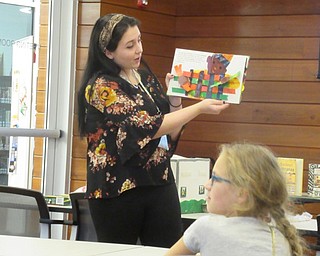 Neighbors | Jessica Harker.Michael Kusalaba librarian Hannah Matulek read "Kwanzaa Celebration Pop Up Book" to community members gathered at the library's first Kwanzaa celebration event on Dec. 27.