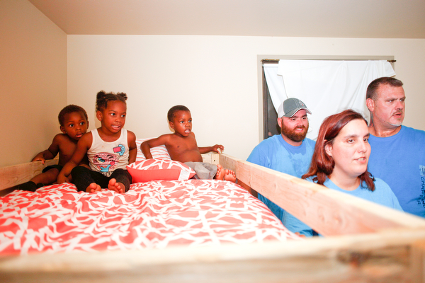 From left, Xyayion Dotson, 3, Miracle Morgan, 5, and Zion Johnson, 4, sit in the top bunk of their new bunk bed while Travis and Emily Leonard, both of Austintown, and Dane "Mickey" Carder, of Canfield, all volunteers from Sleep in Heavenly Peace, stand next to the bunk bed in the kids' home in Campbell on Saturday night. Sleep in Heavenly Peace measured, cut, and stained the pieces of the bed during the day and then brought the pieces to the home and built the bunk bed there at night. Prior to receiving the bunk bed, the three children were sharing one mattress.