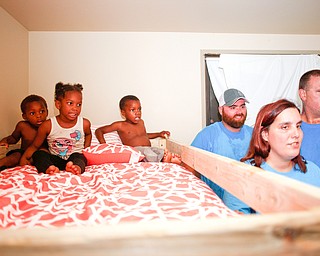 From left, Xyayion Dotson, 3, Miracle Morgan, 5, and Zion Johnson, 4, sit in the top bunk of their new bunk bed while Travis and Emily Leonard, both of Austintown, and Dane "Mickey" Carder, of Canfield, all volunteers from Sleep in Heavenly Peace, stand next to the bunk bed in the kids' home in Campbell on Saturday night. Sleep in Heavenly Peace measured, cut, and stained the pieces of the bed during the day and then brought the pieces to the home and built the bunk bed there at night. Prior to receiving the bunk bed, the three children were sharing one mattress.