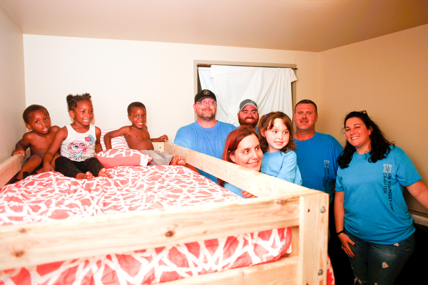 From left, Xyayion Dotson, 3, Miracle Morgan, 5, and Zion Johnson, 4, sit in the top bunk of their new bunk bed while volunteers from Sleep in Heavenly Peace, stand next to the bunk bed in the kids' home in Campbell on Saturday night. Sleep in Heavenly Peace measured, cut, and stained the pieces of the bed during the day and then brought the pieces to the home and built the bunk bed there at night. Prior to receiving the bunk bed, the three children were sharing one mattress.