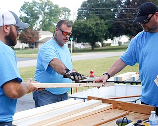 From left, Travis Leonard, of Austintown, Dane "Mickey" Carder, of Canfield, and Jeff Watkins, of Cornersburg, all of the group Sleep in Heavenly Peace lay out pieces of wood for a bunk bed they're building for local children Saturday afternoon at Leonard's house.