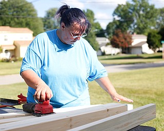 Brenda Miller, of Niles, sands a piece of wood for a bunk bed she's helping to build with the group Sleep in Heavenly Peace for local children Saturday afternoon at the house of Travis Leonard, another group member, in Austintown.