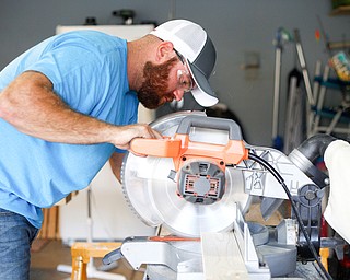 Travis Leonard, of Austintown, cuts a piece of wood  for a bunk bed he's helping to build with the group Sleep in Heavenly Peace for local children Saturday afternoon at his house.