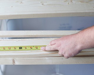 Jeff Watkins, of Cornersburg, measures out a plank of wood for a bunk bed he's helping to build with the group Sleep in Heavenly Peace for local children Saturday afternoon at the house of Travis Leonard, another group member, in Austintown.