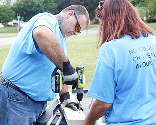 Dane "Mickey" Carder, of Canfield, drills holes into a piece of wood with Amanda Watkins, of Cornersburg, to make a bunk bed with the group Sleep in Heavenly Peace for local children Saturday afternoon at the house of Travis Leonard, another group member, in Austintown.