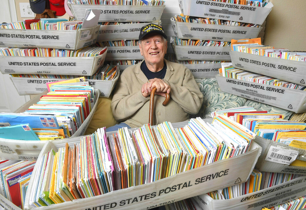 In this Tuesday, Jan. 8, 2019, photo, Duane Sherman, 96, poses at home with a small fraction of the 50,000 birthday cards he's received after his daughter's social media request for people to send him cards to cheer him up on his birthday went viral in Fullerton, Calif.