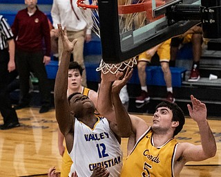 DIANNA OATRIDGE | THE VINDICATOR  Valley Christian's Tyrone Lindsey (12) reaches for a rebound off the rim in front of Cardinal Mooney's Pete Haas (5) during the Eagles' 58-56 victory in Youngstown on Tuesday.