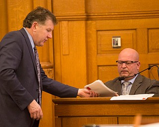Assistant Prosecutor Chris Becker hands photos from the crime scene to witness Peter Pizzulo, former detective with the Trumbull County Sheriff's Office, during Claudia Hoerig's trial on Wednesday. EMILY MATTHEWS | THE VINDICATOR