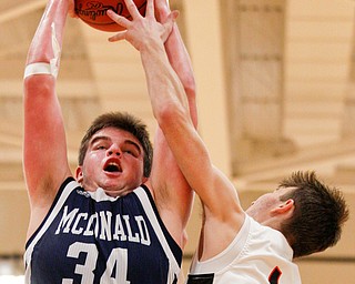 McDonald's Jake Portolese catches a rebound as Mineral Ridge's Austin Governor reaches for the ball during their game at Mineral Ridge on Tuesday night. EMILY MATTHEWS | THE VINDICATOR