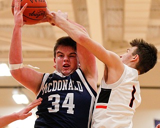 McDonald's Jake Portolese catches a rebound as Mineral Ridge's Austin Governor reaches for the ball during their game at Mineral Ridge on Tuesday night. EMILY MATTHEWS | THE VINDICATOR