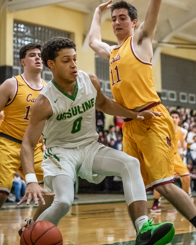 DIANNA OATRIDGE | THE VINDICATOR Ursuline's Devan Keevey (0) drives the baseline between Cardinal Mooney's Mike Pelini (14) and Anthony Fire (11) during Friday's game at Ursuline High School Gymnasium.