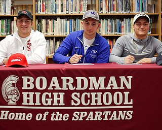 From left, Michael O'Horo, Alex Huzicka, and Kareem Hamdan sign to Saginaw Valley St., Notre Dame College, and Clarion University, respectively, during a signing ceremony in the Boardman High School library on Wednesday. EMILY MATTHEWS | THE VINDICATOR