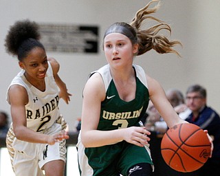 Ursuline's Jamie Nelson drives the ball while Warren G. Harding's Diamond Phillips runs after her during their game at Warren G. Harding High School on Monday night. EMILY MATTHEWS | THE VINDICATOR