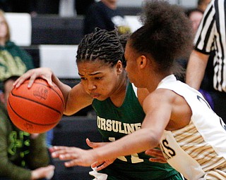 Ursuline's Dayshanette Harris dribbles the ball while Warren G. Harding's Diamond Phillips tries to block her during their game at Warren G. Harding High School on Monday night. EMILY MATTHEWS | THE VINDICATOR