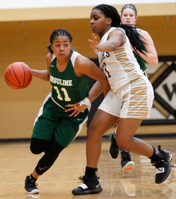Ursuline's Dayshanette Harris drives the ball while Warren G. Harding's Braeden Morris tries to block her during their game at Warren G. Harding High School on Monday night. EMILY MATTHEWS | THE VINDICATOR