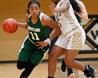 Ursuline's Dayshanette Harris drives the ball while Warren G. Harding's Braeden Morris tries to block her during their game at Warren G. Harding High School on Monday night. EMILY MATTHEWS | THE VINDICATOR