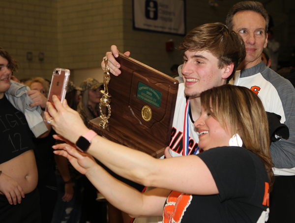 Springfield’s Clay Medvec takes a picture with his mom Angie Medvec with the District Championship trophy after they defeated Lowellville at the Struthers Fieldhouse on Friday night.  Dustin Livesay  |  The Vindicator  3/8/19  Struthers