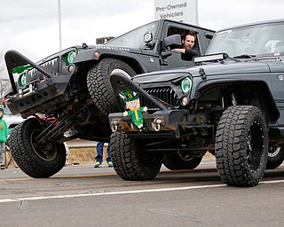 One Jeep driver gets his wheel on top of another driver's wheel as they drive down Market Street during the Mahoning Valley St. Patrick's Day Parade in Boardman on Sunday afternoon. EMILY MATTHEWS | THE VINDICATOR