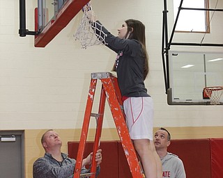 Neighbors | Abby Slanker.Canfield Village Middle School eighth-grade girls basketball player Haydyn Merritt cut down the net, as coaches Jim Harmon (left) and Mike Merritt (right) looked on, to celebrate the team’s 2019 AAC championship on Feb. 18.