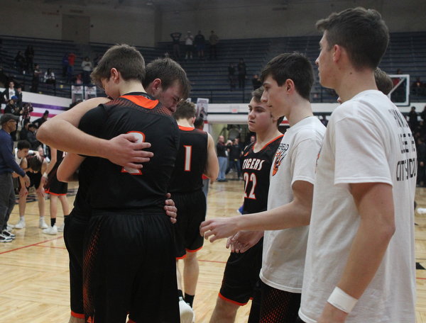 Springfield senior Shane Eynon (12) gets hugged by his teammates as time ran out during the second half of Friday night's Regional Championship matchup against Richmond at the Canton Fieldhouse. The Tigers lost 46-43.  Dustin Livesay   |   The Vindicator  3/15/19  Canton.