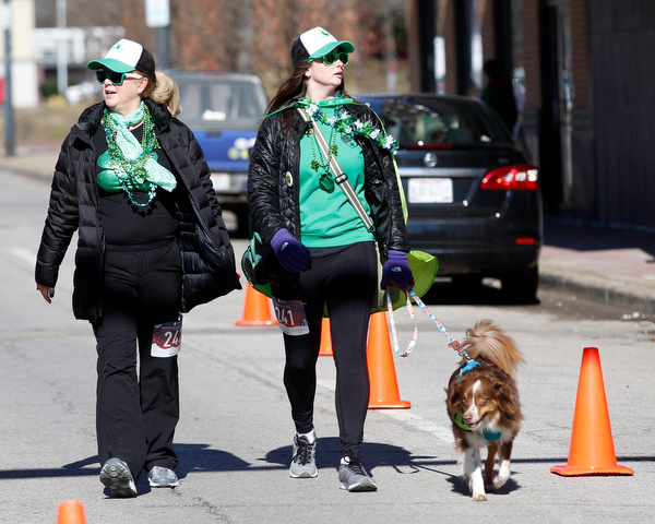 Jill Lewis, left, and her daughter Sydney Lewis, both of Liberty, walk with their mini Australian Shepherd Tucker in the inaugural Youngstown St. Paddy's Day 5K Fun Run and Walk on Sunday morning. EMILY MATTHEWS | THE VINDICATOR