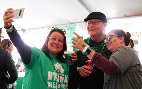 Jess Thomas, left, of Boardman, takes a selfie with Ralph and Rachael Murphy, of Struthers, and their green beer at Shamrock the Block on Sunday afternoon. EMILY MATTHEWS | THE VINDICATOR