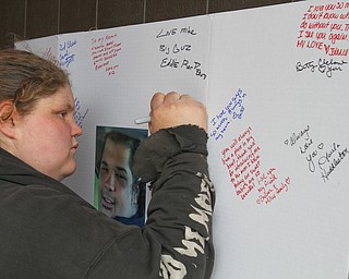 William D. Lewis The Vindicator  Jamie Burke of Struthers signs a poster during a 3-24-19 vigil for a Campbell father and son who were killed ina  car crash.