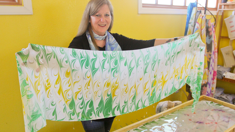 Peggy Humes shows off custom-dyed silk scarves at the Rust Belt Print Shop she and her husband, Mike, operate at the B&O property off Mahoning Avenue near downtown Youngstown.
