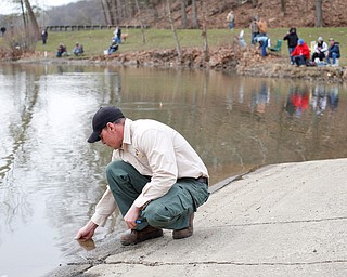 Daniel Kovalaske, fish catcher and coordinator with Ohio Division of Wildlife, measures the temperature of Lake Glacier before releasing rainbow trout into the lake on Thursday. He said the lake was 49 degrees fahrenheit and the water the fish were in was 52 degrees, which was okay because they could handle a ten degree difference. EMILY MATTHEWS | THE VINDICATOR