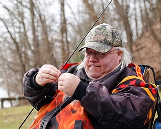 Gerald Kelly, of the West Side, ties his line in preparation to fish for rainbow trout after they were released into Lake Glacier on Thursday. EMILY MATTHEWS | THE VINDICATOR