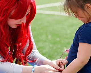 Ashley Cunningham, a YSU junior studying journalism, dressed as Ariel from The Little Mermaid, puts a bracelet on Ava Rainey, 5, of Brookfield, at Farmers National Bank Field during YSU Relay for Life Saturday afternoon. EMILY MATTHEWS | THE VINDICATOR