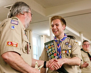 Eagle Scout Colin Russell, of troop 60, shakes hands with Byron Harnishfeger, District Advancement Chairman, as he's recognized with other Eagle Scouts at the Whispering Pines Recognition Dinner in St. James Episcopal Church in Boardman on Sunday. EMILY MATTHEWS | THE VINDICATOR