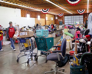 Volunteers Sonny Nabb, left, of Boardman, and Bill Varga, of Columbiana, arrange tools, sports equipment, and other outdoor items that will be for sale at the Angels for Animals garage sale at the Canfield Fairgrounds on Tuesday morning. The garage sale will take place Friday through Sunday at the fairgrounds. EMILY MATTHEWS | THE VINDICATOR