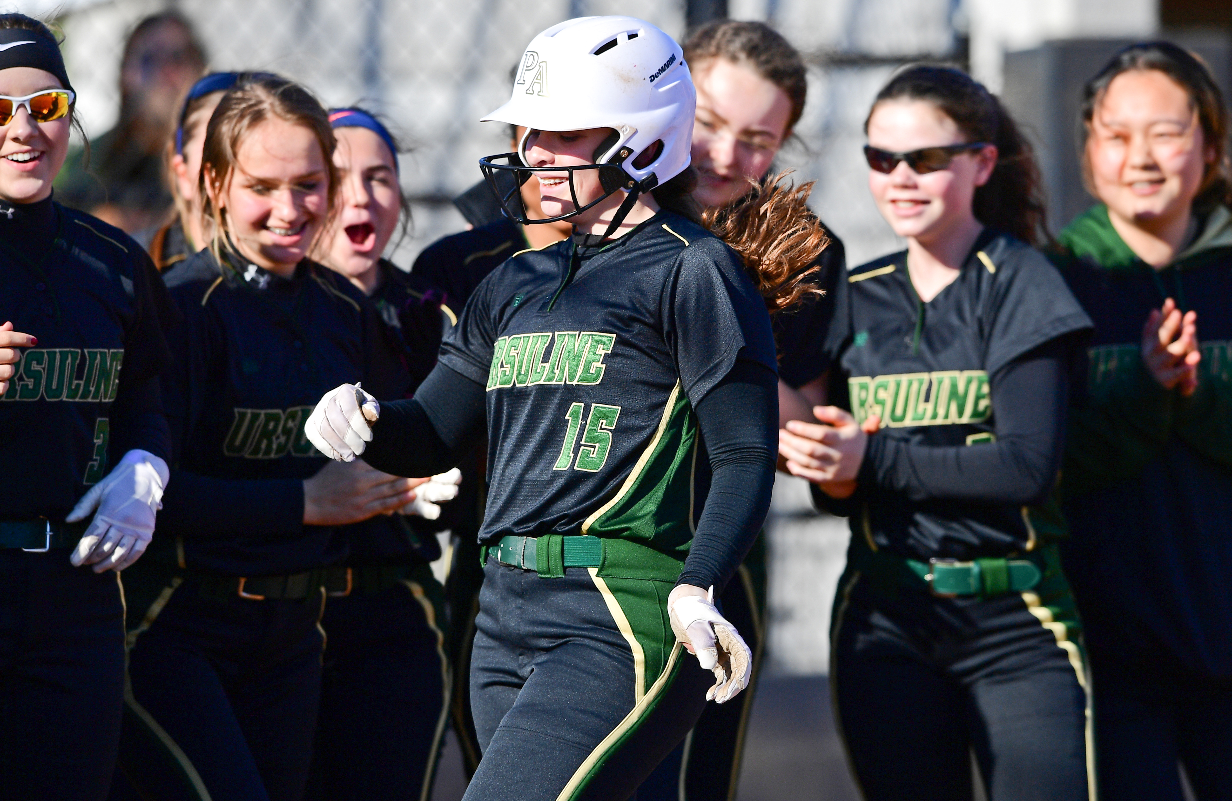 Ursuline High School's Emily Holland is congratulated by her teammates after belting a solo home run in the second inning of Tuesday's softball game against rival Cardinal Mooney at Youngstown State University's Covelli Sports Complex. The Irish won 11-1.