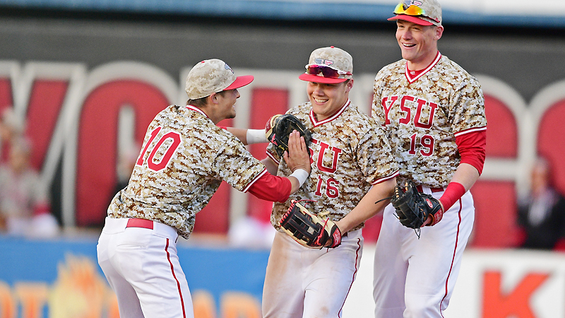 Youngstown State University's Blaze Glenn, center, is congratulated by Cody Dennis, left, and Trevor Wiersma after going over the fence and making the catch in the eighth inning of Wednesday night's game against the University of Toledo at Eastwood Field in Niles. YSU beat the Rockets, 5-3.