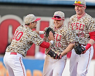 Youngstown State University's Blaze Glenn, center, is congratulated by Cody Dennis, left, and Trevor Wiersma after going over the fence and making the catch in the eighth inning of Wednesday night's game against the University of Toledo at Eastwood Field in Niles. YSU beat the Rockets, 5-3.