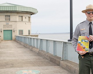 Bill Spring, resource manager at Mosquito Creek Lake, stands in front of the control tower at the lake while he holds a flier for the lake's 75th anniversary event taking place June 15. 