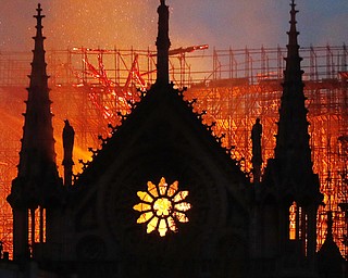 Flames and smoke rise from Notre Dame Cathedral as it burns in Paris on Monday. Massive plumes of yellow brown smoke filled the air above the cathedral and ash fell on tourists and others around the island that marks the center of Paris. 