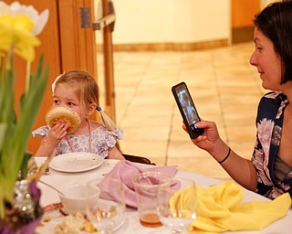 Beth Hawks, right, of Canfield, takes a photo of her daughter Claire Hawks, 2, as she eats a bagel at the annual Easter Brunch at Fellows Riverside Gardens on Sunday. EMILY MATTHEWS | THE VINDICATOR