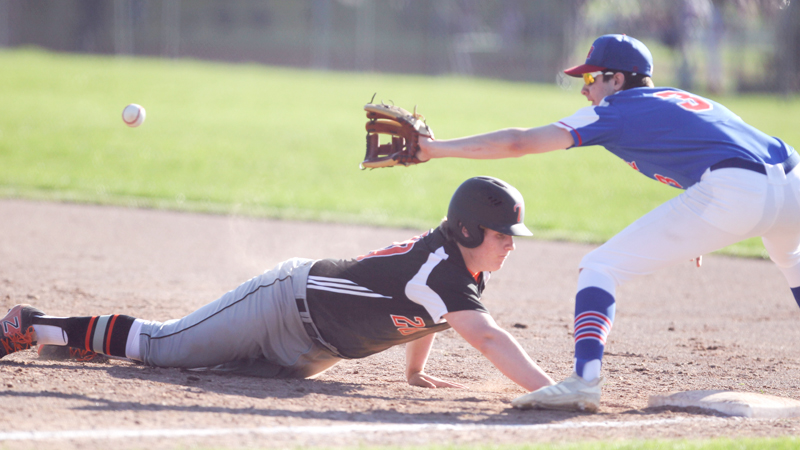 Chris Thompson (20)  of Springfield High School slides safely back to first underneath the tag by Dan Windham (3) of Western Reserve High School during Monday afternoon's game. Springfield won 3-1.