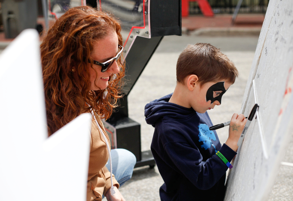 Dominic Zenobi, 6, writes his name on a penguin-shaped board with his mother Ashley Zenobi behind him at Federal Frenzy on Saturday. EMILY MATTHEWS | THE VINDICATOR