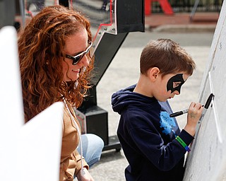 Dominic Zenobi, 6, writes his name on a penguin-shaped board with his mother Ashley Zenobi behind him at Federal Frenzy on Saturday. EMILY MATTHEWS | THE VINDICATOR