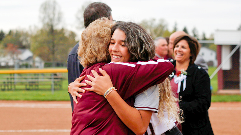 Alicia Saxton, right, a senior on the Boardman softball team, hugs school district Athletic Director Denise Gorski during senior night at the newly renovated  softball field.  The parents of players worked two weekends to install a new wind screen and work on the field’s surface and drainage.  
