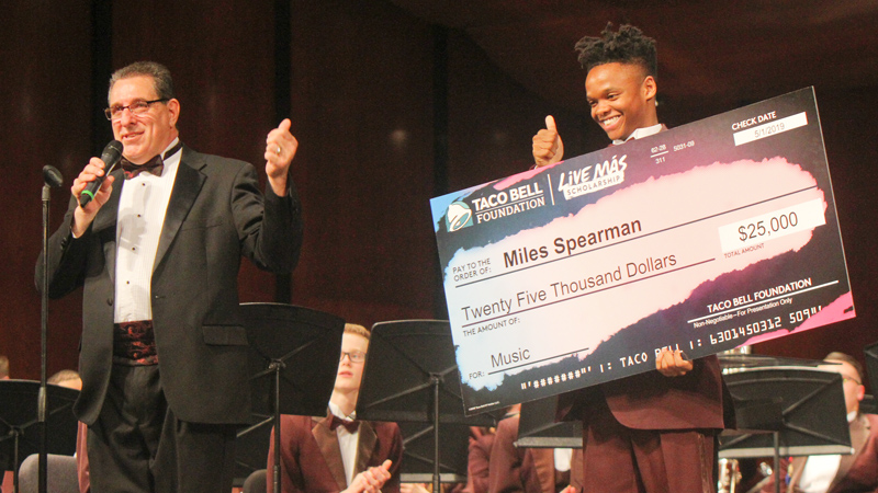 Boardman senior Miles Spearman is all smiles and a thumbs up after receiving a $25,000 scholarship from Taco Bell at the very end of the Boardman band concert on Wednesday night. Making the announcement on the stage is band director Tom Ruggieri. 
