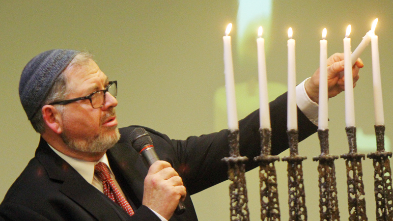 Rabbi Joseph Schonberger lights a candle during the Shoah Memorial Ceremony at the Jewish Community Center on Sunday. Shoah is the Hebrew term for the Holocaust.