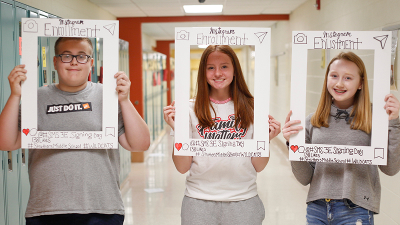 Colin Mateo, 13, left, Faith Stellato, 14, and Brooke Adams, 14, all Struthers eighth-graders, hold photo frames during a career event at the middle school showing what path they would choose. 
