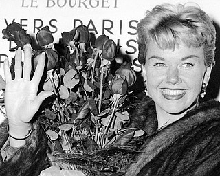 In this April 15, 1955, file photo, American actress and singer Doris Day holds a bouquet of roses at Le Bourget Airport in Paris after flying in from London. The Doris Day Animal Foundation confirmed Day died early Monday, May 13, 2019, at her home in Carmel Valley, Calif. She was 97.  