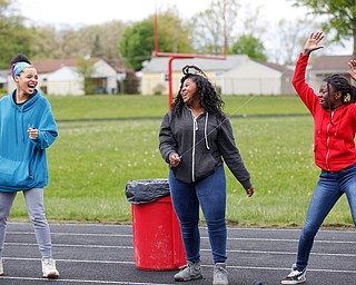 From left, Nevaeh Williams, 16, an 11th grader at Chaney High School, Nakaia McRae, 16, an 11th grader, and Alaja Johnson, 17, an 11th grader, dance as they fly kites during a fundraiser for Save the Children, an organization that helps child refugees, on the track at Chaney High School on Tuesday afternoon. EMILY MATTHEWS | THE VINDICATOR
